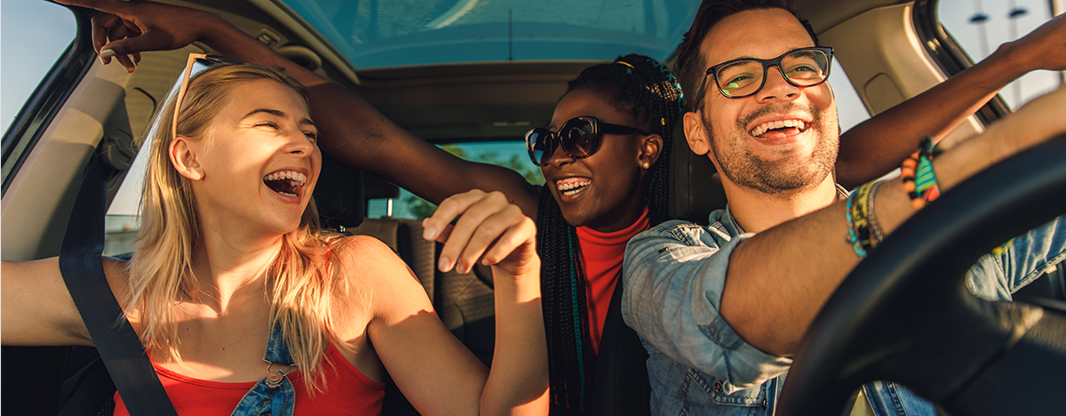 Group of happy friends riding in a car