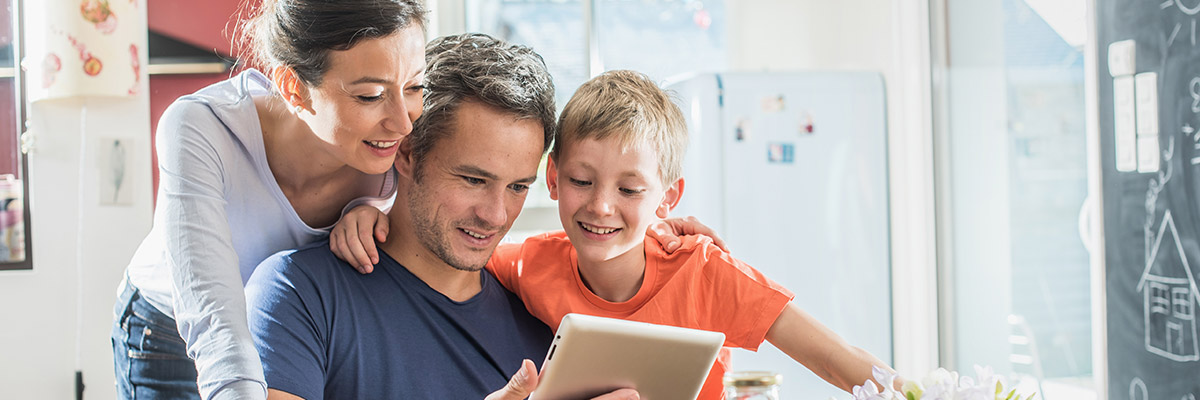 A family using a tablet while having breakfast in the kitchen
