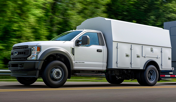 2021 Ford Super Duty Chassis Cab with flatbed body and flatbed trailer being driven on road