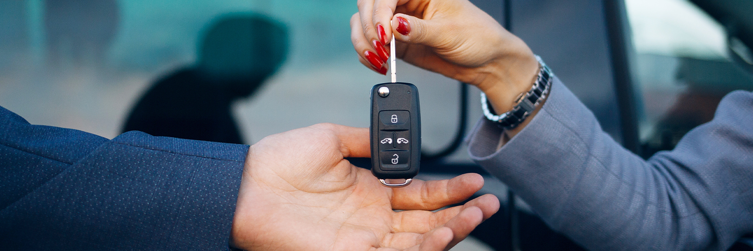 Dealership employee handing over keys to a rental