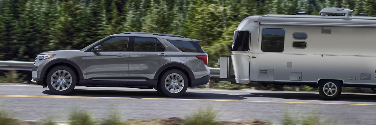 A 2025 Ford Explorer® SUV being driven on the highway hauling a trailer