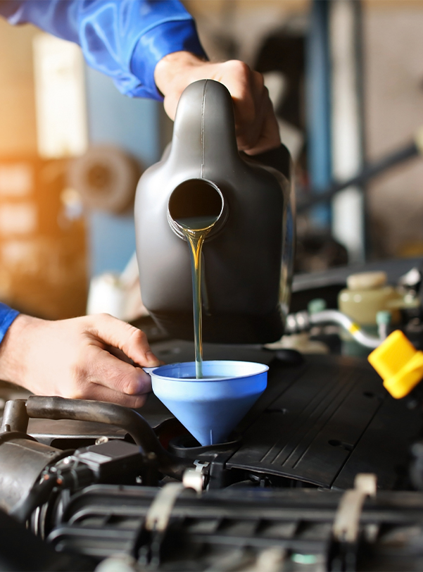 Service technician pouring oil into a vehicle